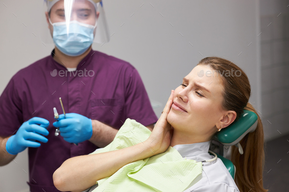 Female patient waiting for an anesthetic injection for a painless tooth treatment in dental clinic