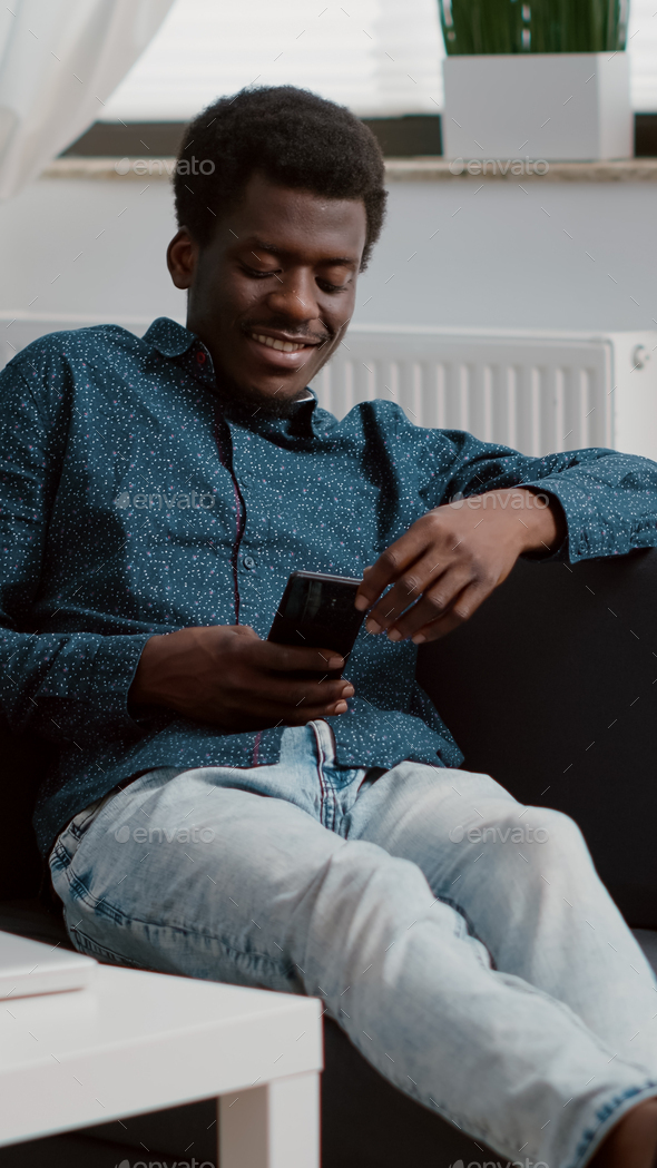African american man with phone in hands looking at online streaming services content