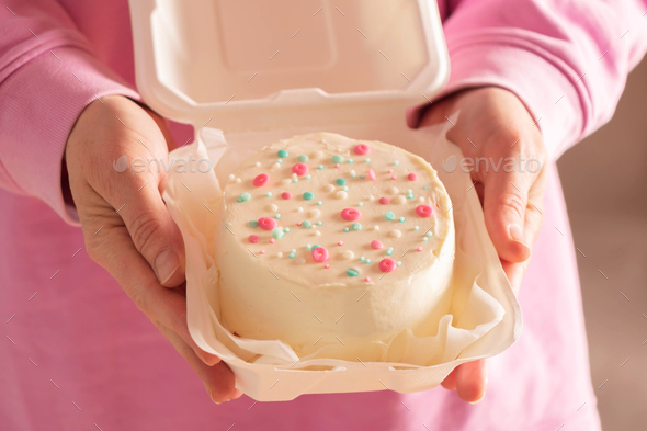 Woman is holding bento cake in her hands. Korean style cakes in box for one person