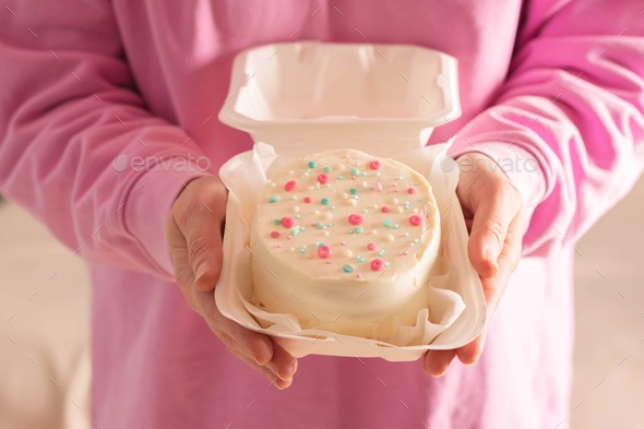 Woman is holding bento cake in her hands. Korean style cakes in box for one person