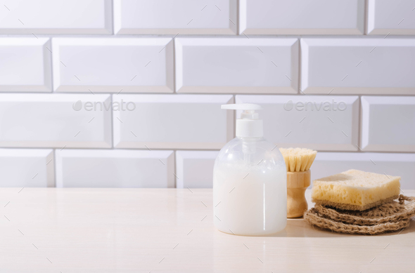 Liquid detergent, natural sponges brush for washing dishes and kitchen utensils on the kitchen table