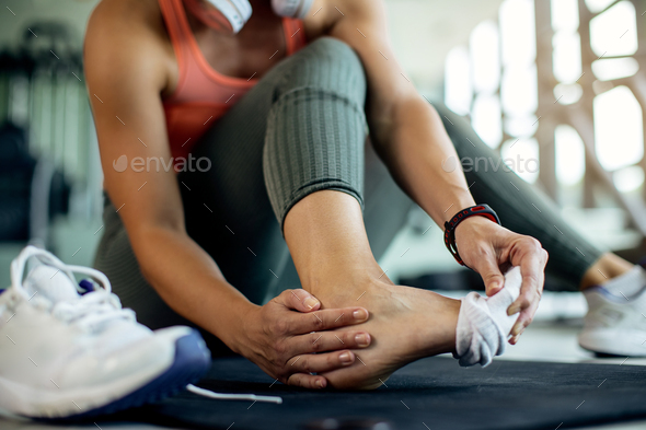 Close-up of athletic woman injured her foot during workout at the gym.