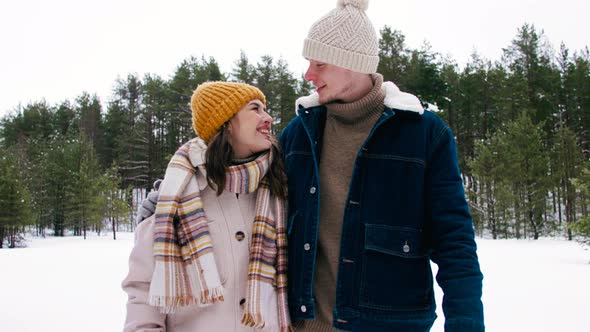 Happy Smiling Couple Walking in Winter Forest