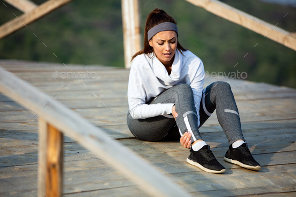 Young athletic woman holding her leg in pain while exercising outdoors. - Stock Photo - Images