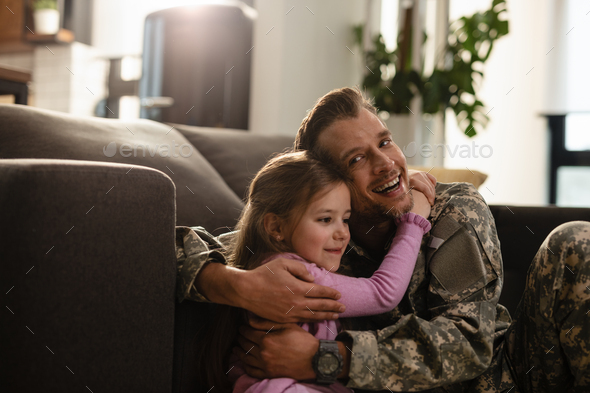 Affectionate little girl and her military father embracing at home.