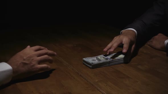 Businessman rejecting money  offered by his partner in the dark - anti bribery concept