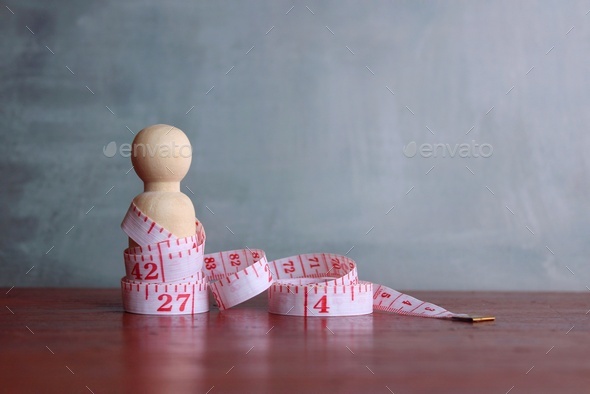 Wooden doll and measuring tape. Copy space for text.