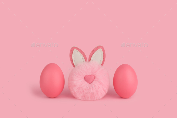  Pink Easter fluffy bunny rabbit and two pink eggs on pink background.