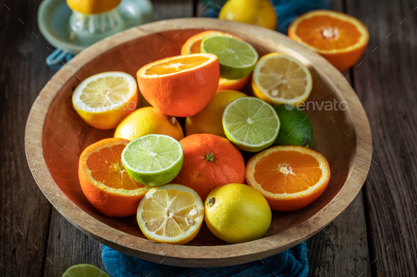 Sweet and sour mix of citrus fruits in wooden bowl.