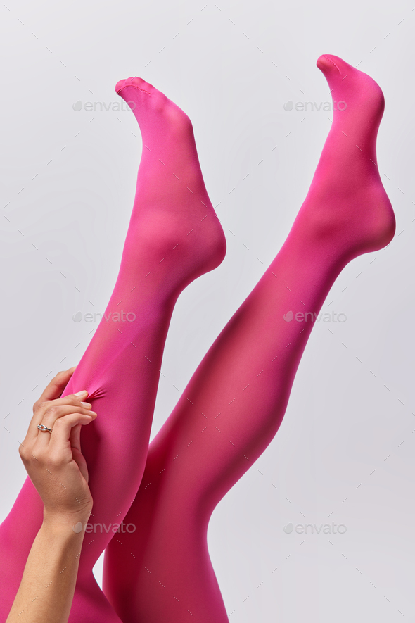 Vertical shot of unrecognizable woman wears pink pantyhose keeps legs  raised up rests after wearing Stock Photo by wayhomestudioo