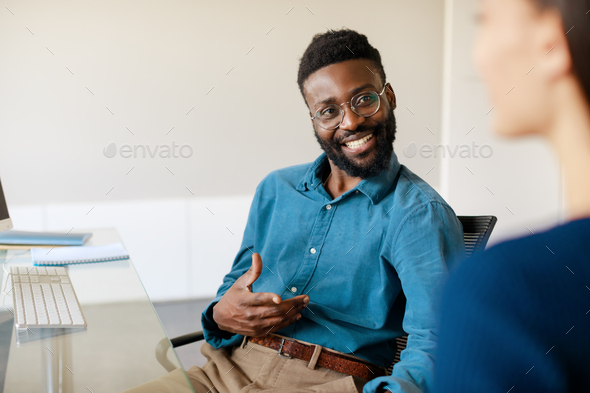 Happy black male hiring manager speaking to vacancy candidate during employment interview at modern