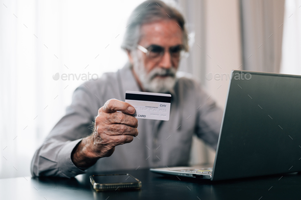 Healthy grandfather using laptop and pay money by credit card