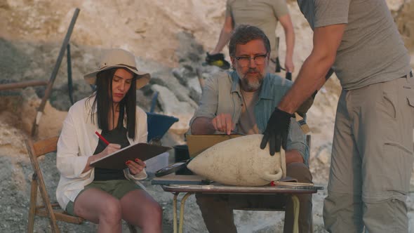 Colleagues Drawing Amphora on Archaeological Site alt