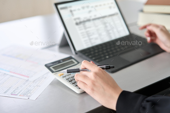 Asian woman using accounting software and calculator