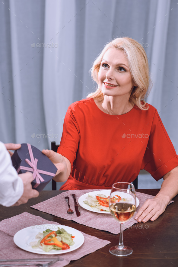 cropped image of husband presenting gift to wife, st valentines day concept
