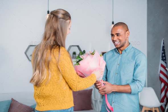 african american boyfriend presenting bouquet to girlfriend