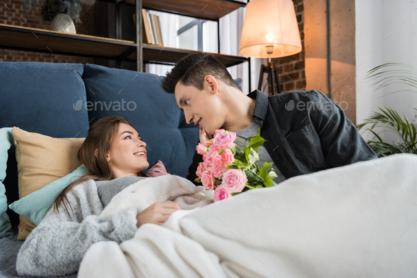 boyfriend presenting bouquet of roses to girlfriend in morning on international womens day