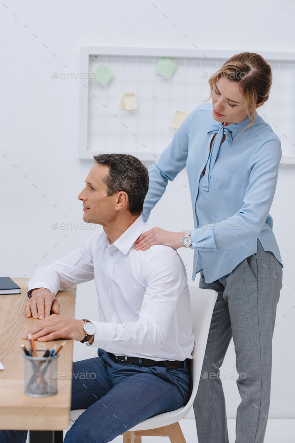 businessman working with laptop at workplace while his secretary doing massage for him
