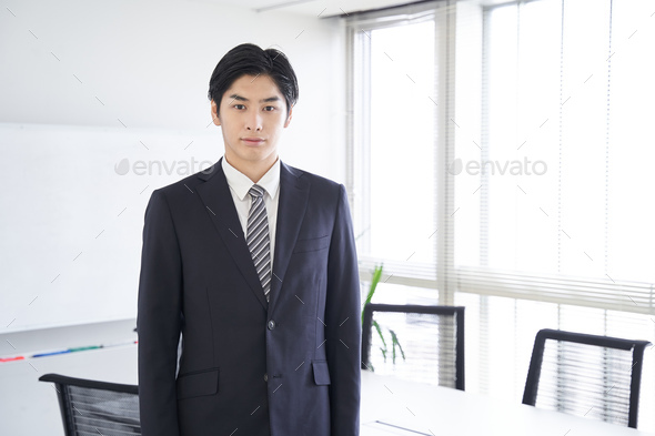 A Japanese male businessman stands in a conference room