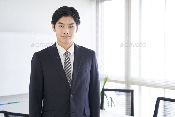 A Japanese male businessman stands in a conference room