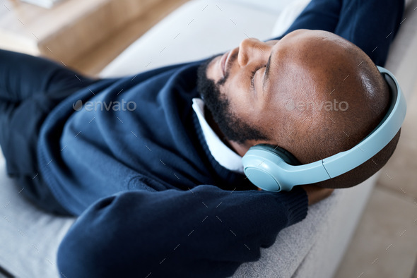 Music top view, headphones and black man on sofa in home living room streaming audio. Meditation, r
