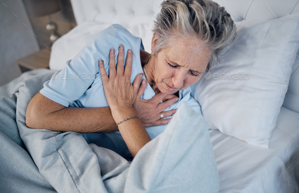 Heart attack, senior woman and chest pain, anxiety or medical emergency in her bedroom. Heartburn,