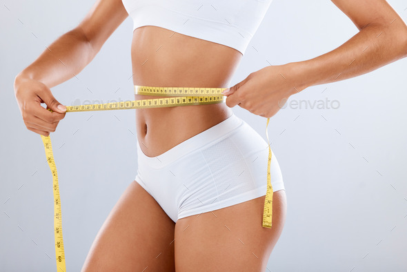 Weightloss, health and woman with measuring tape in a studio for her diet,  exercise or wellness. Fi Stock Photo by YuriArcursPeopleimages