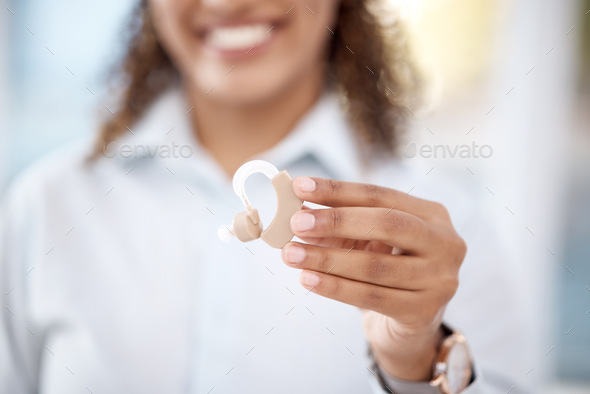 Hand, hearing aid and disability with a black woman holding a listening device in a healthcare clin