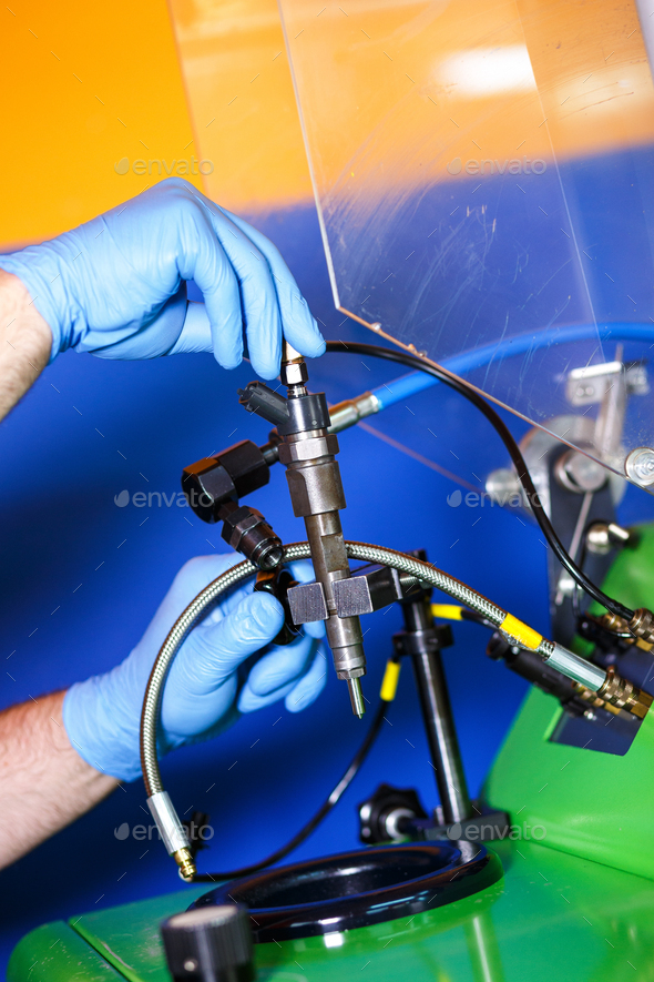 Professional mechanic testing diesel injector in his Stock Photo by zoranzeremski