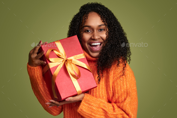 Smiling ethnic woman with present in studio - Stock Photo - Images