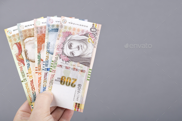 Peruvian money in the hand on a gray background - Stock Photo - Images