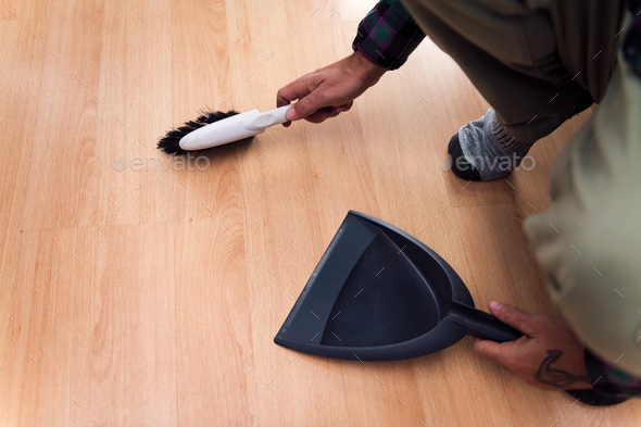 person sweeping the floor with a brush and dustpan