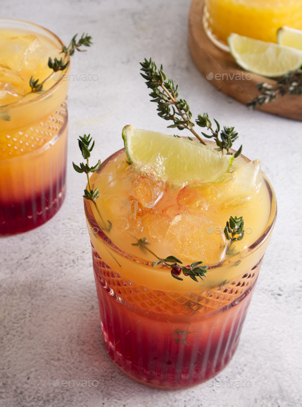 Cocktails with ice, orange juice and grenadine syrup decorated with berries and herbs close-up
