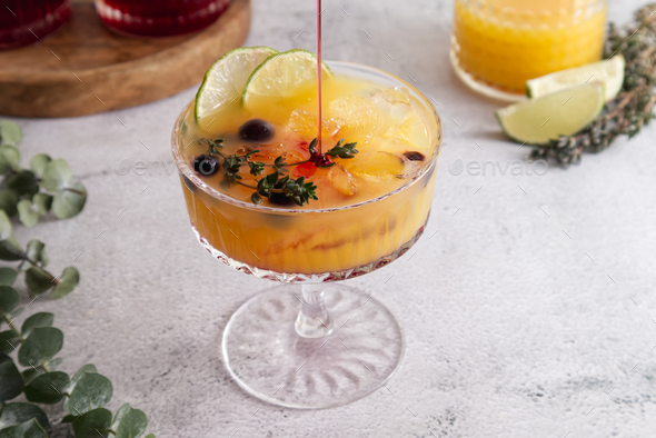 Fresh cocktail with ice, orange juice and grenadine syrup decorated with berries close-up