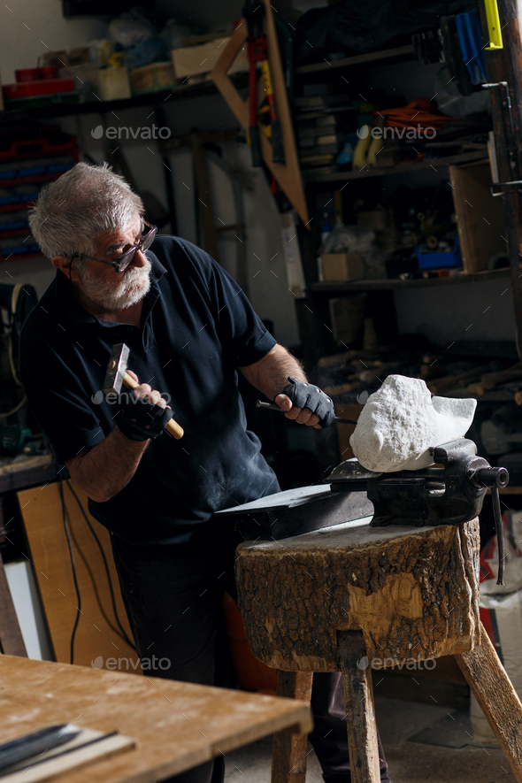 Senior sculptor working on his marble sculpture in his with