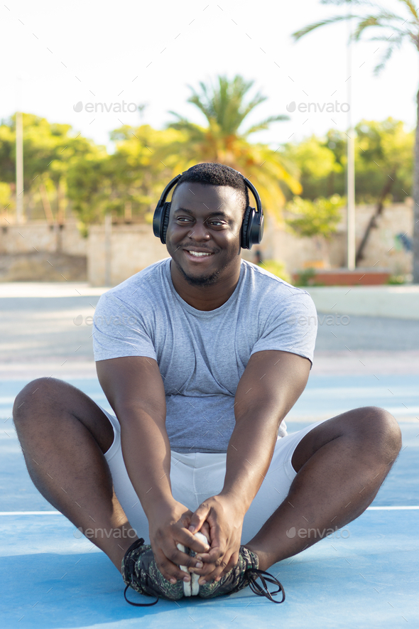 Young black male in headphones working out in a park