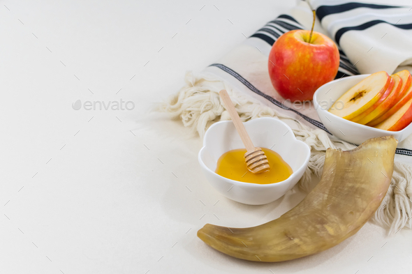 Closeup shot of the shofar, sweet honey and apples on the prayer shawl