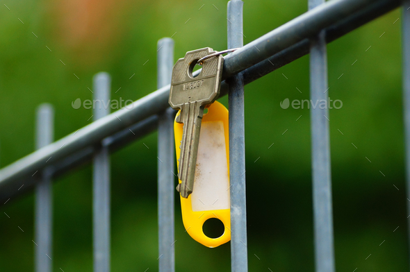 A lost key with a yellow badge on a fence.