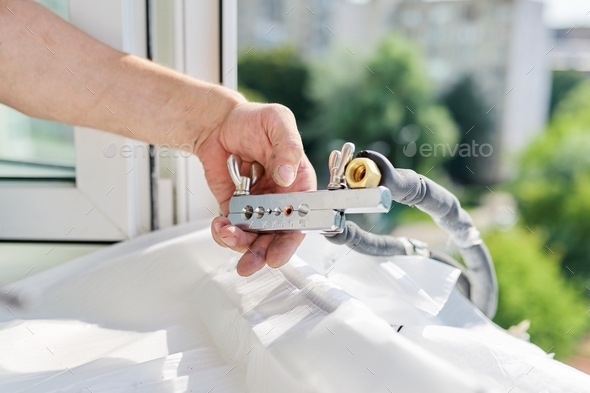 Installing an air conditioner in an apartment office, close-up of an technician hands