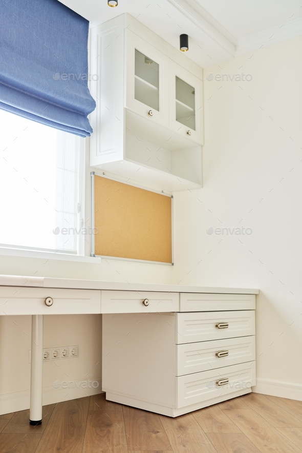 Interior of room, workplace near window, furniture, desk, blue roman blind, wall shelves
