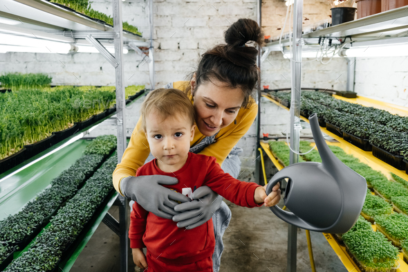 Woman with baby boy working on microgreen indoor farm