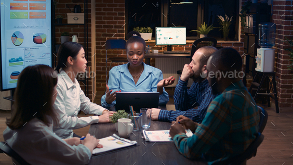Diverse coworkers brainstorming, listening to executive in business meeting