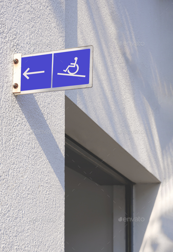 Disabled Wheelchair Sign and arrow label on entrance building wall for