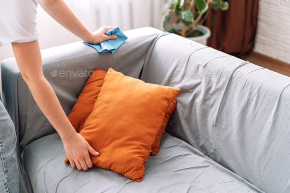 Lady cleans the sofa with a blue rag