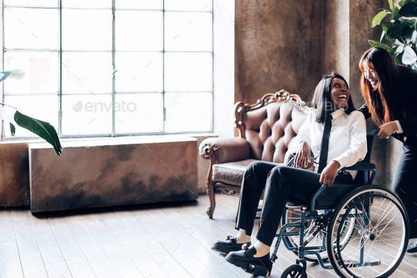 Good Relationship between Two Friends: Young Asian Woman Playfully Pushing Her Friend in Wheelchair