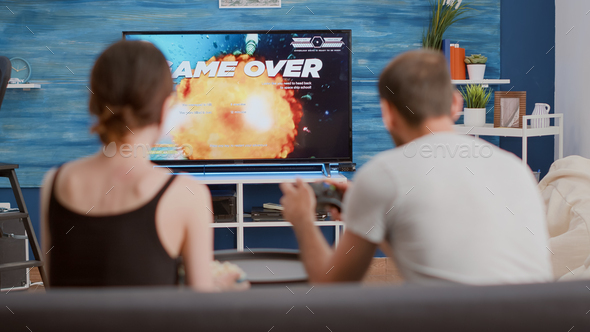 Man beating woman at video games with controller on console over blue  background. Boyfriend celebrating win and girlfriend feeling disappointed  about losing online gameplay in studio Stock Photo - Alamy