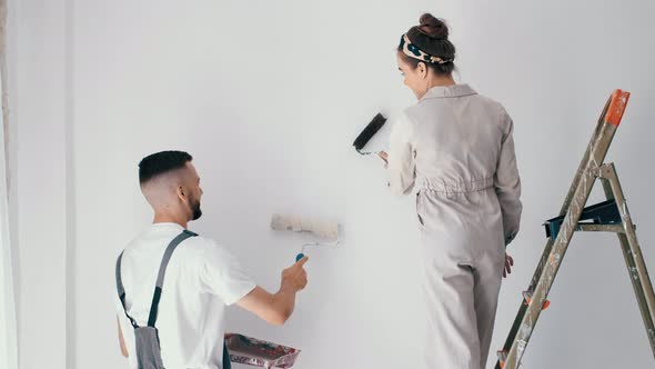 Wife Standing on a Ladder While Her Husband Paints the Wall alt
