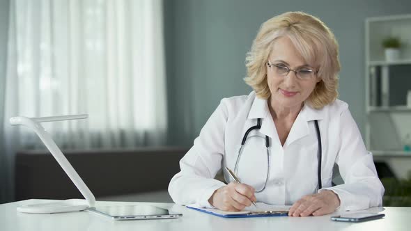 Female Physician Making Prescriptions Filling out Patients Medical Records alt