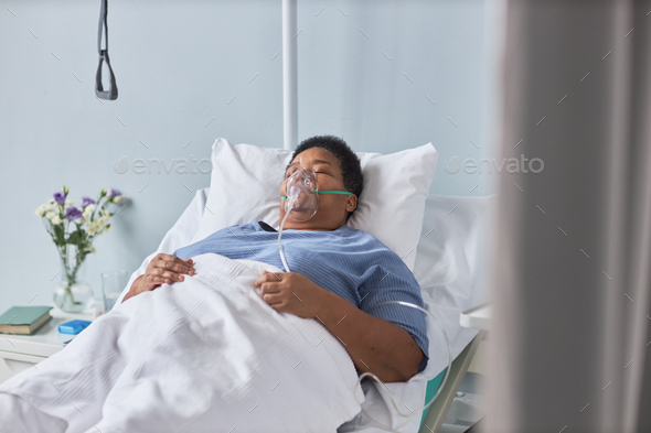 Senior African American woman laying on bed in hospital room with oxygen support