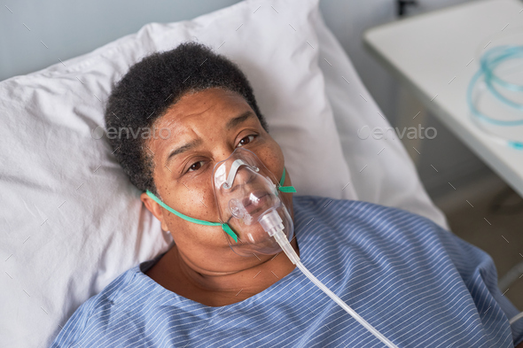 African American senior woman in hospital room looking at camera, oxygen support